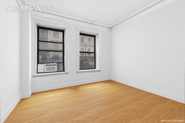 spare room with crown molding, baseboards, wood finished floors, and cooling unit