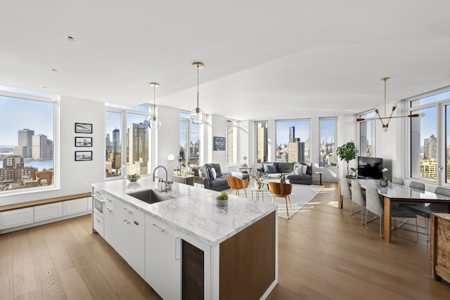 kitchen featuring light wood-type flooring, a sink, white cabinetry, and a notable chandelier