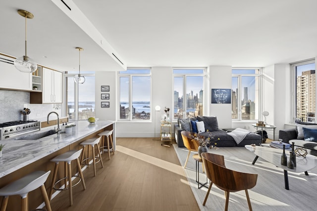 interior space with a breakfast bar, wood finished floors, stainless steel stove, white cabinetry, and a sink