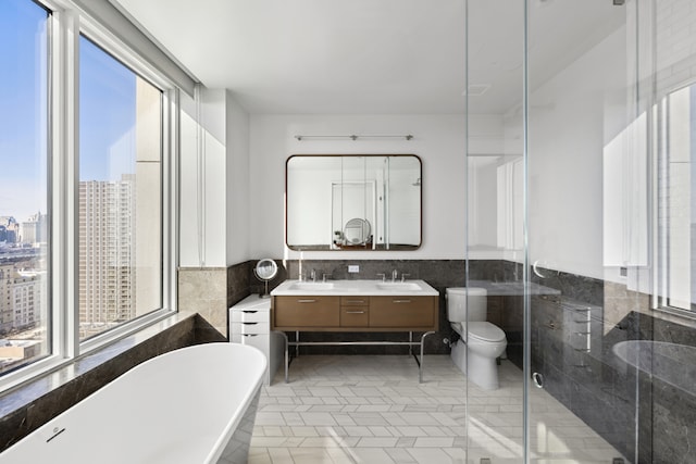 bathroom featuring a view of city, tile walls, double vanity, a freestanding bath, and a sink