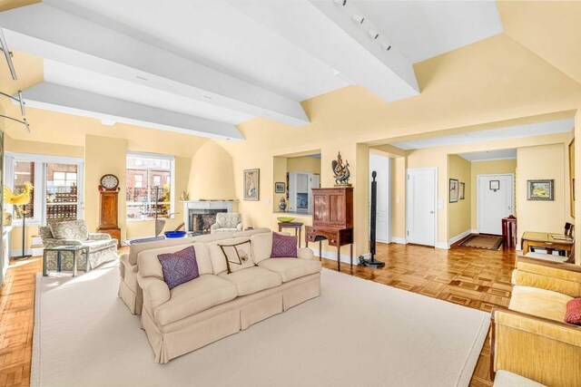 19 E 88th St Unit 15G, New York City, NY 10128 - living room featuring vaulted ceiling with beams, a fireplace, and baseboards