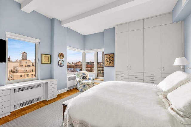 19 E 88th St Unit 15G, New York City, NY 10128 - bedroom with radiator, beam ceiling, a closet, a view of city, and baseboards