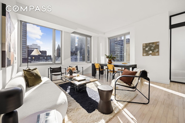 living room with a view of city, plenty of natural light, baseboards, and wood finished floors