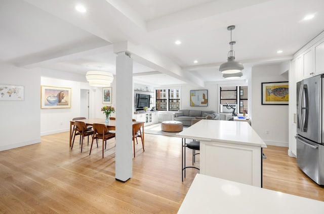 kitchen featuring white cabinets, a kitchen island, a kitchen breakfast bar, freestanding refrigerator, and light wood-type flooring