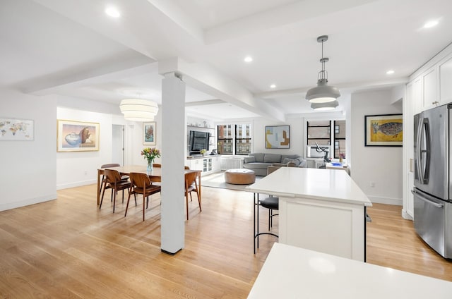 kitchen featuring light wood-style flooring, a center island, freestanding refrigerator, white cabinets, and a breakfast bar area