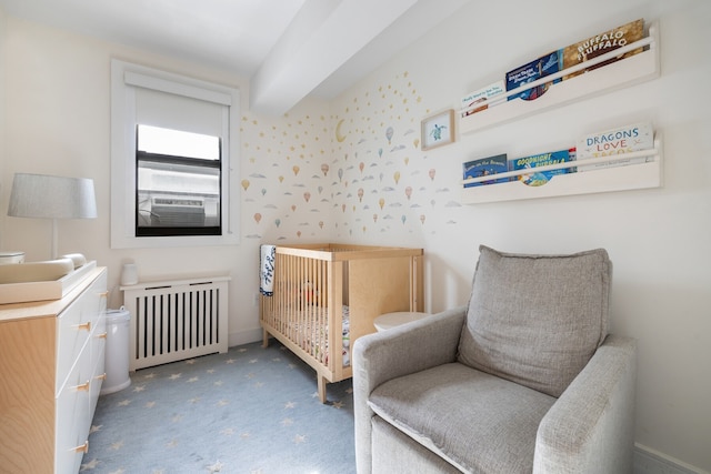 bedroom with radiator heating unit, carpet, and a crib