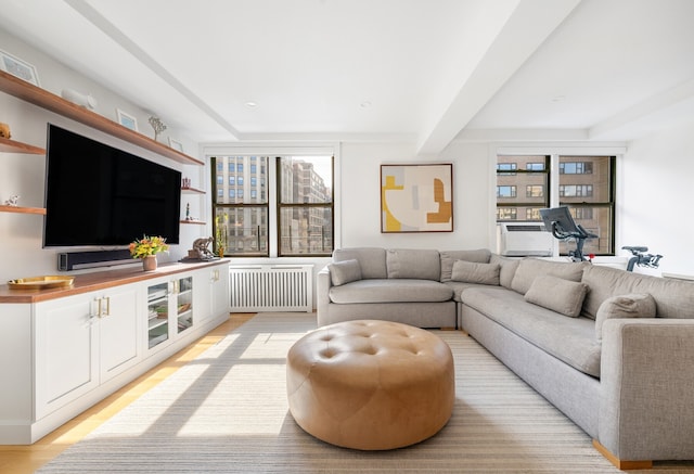 living room with a healthy amount of sunlight, light wood finished floors, beamed ceiling, and radiator