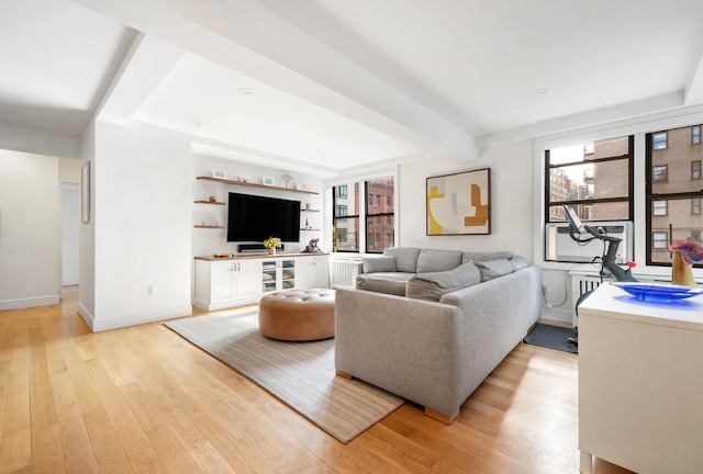 living area with light wood-style floors, beam ceiling, and baseboards