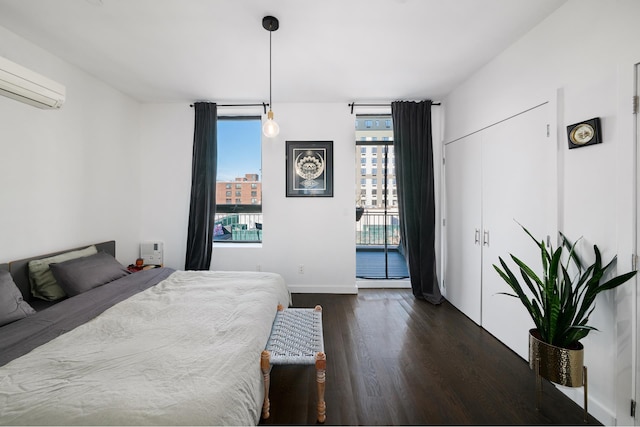 bedroom with dark wood-type flooring, a wall unit AC, and access to outside