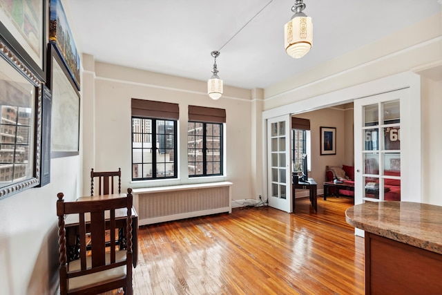 dining room with light wood-type flooring, french doors, and radiator