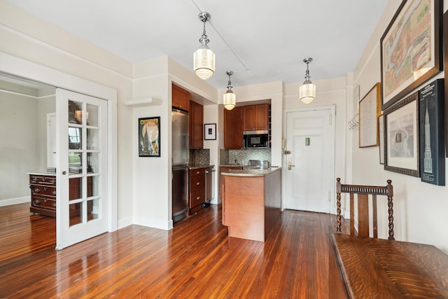 kitchen featuring decorative light fixtures, dark wood finished floors, a center island, appliances with stainless steel finishes, and decorative backsplash