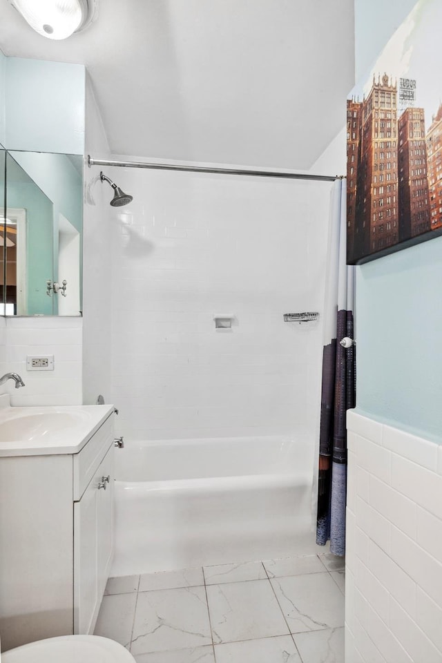 full bath featuring vanity, tile walls, shower / bathtub combination with curtain, and marble finish floor