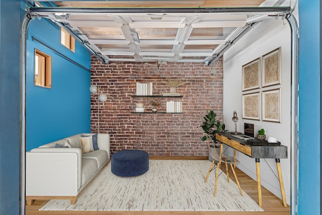 home office featuring a garage, brick wall, and wood finished floors