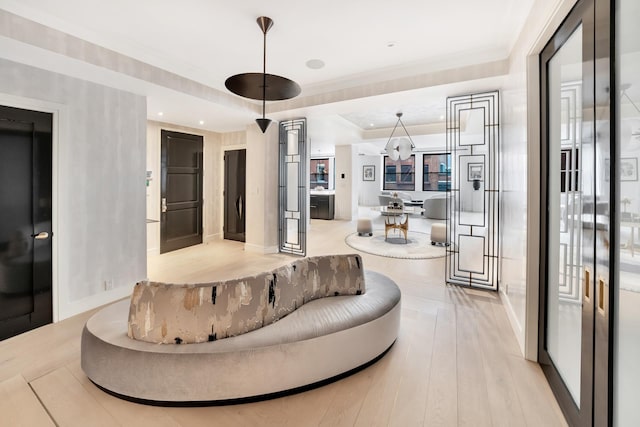 living room with light wood-style floors, a tray ceiling, and ornamental molding