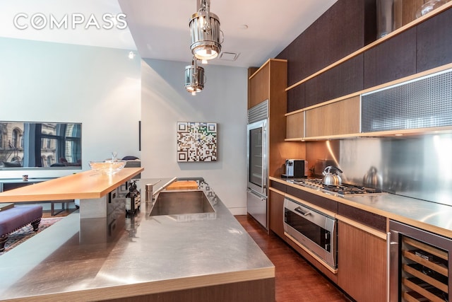 kitchen featuring stainless steel countertops, wine cooler, built in appliances, and dark wood finished floors