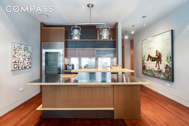 kitchen featuring open shelves, stainless steel built in fridge, a center island, and dark wood-style flooring