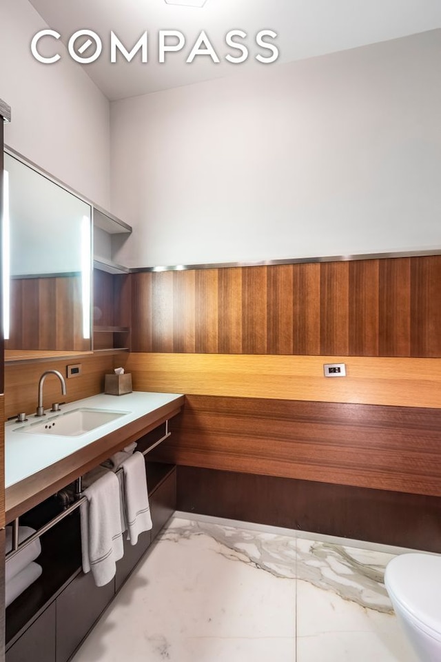 interior space featuring wooden walls, marble finish floor, light countertops, and a sink