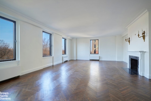 unfurnished living room featuring radiator, a fireplace, baseboards, and ornamental molding