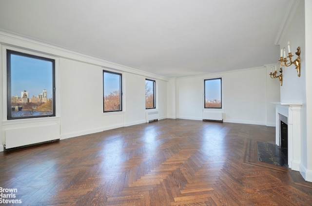 unfurnished living room featuring radiator heating unit, plenty of natural light, a fireplace with flush hearth, and ornamental molding