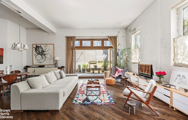 living area with brick wall, a chandelier, and wood finished floors