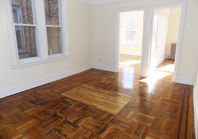 unfurnished room featuring radiator and baseboards