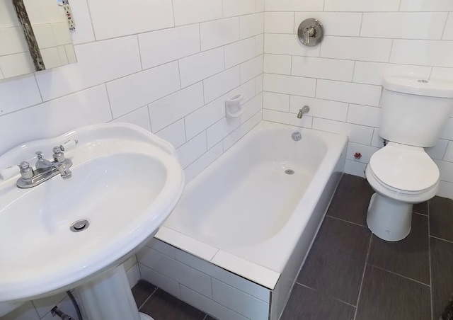 bathroom featuring toilet, a sink, and tile walls