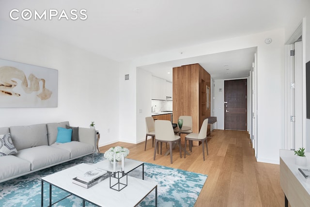 living area featuring visible vents, light wood-type flooring, and baseboards