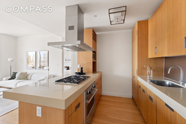 kitchen with a peninsula, light wood-style flooring, a sink, stainless steel appliances, and island range hood