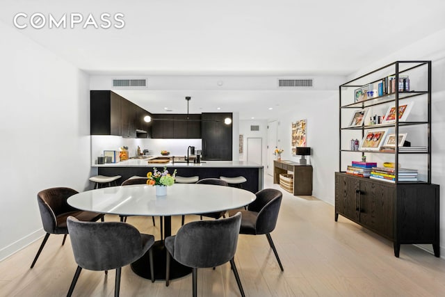 dining area featuring light wood finished floors, baseboards, and visible vents