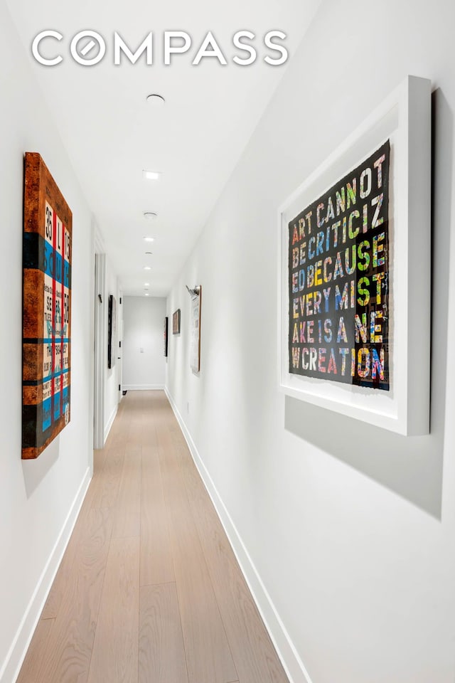 hallway featuring light wood finished floors and baseboards