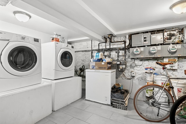 washroom featuring electric panel, washing machine and dryer, and light tile patterned flooring