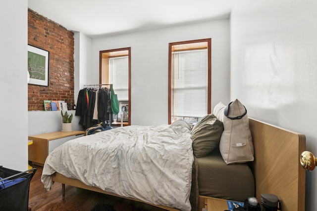 bedroom with wood finished floors and brick wall