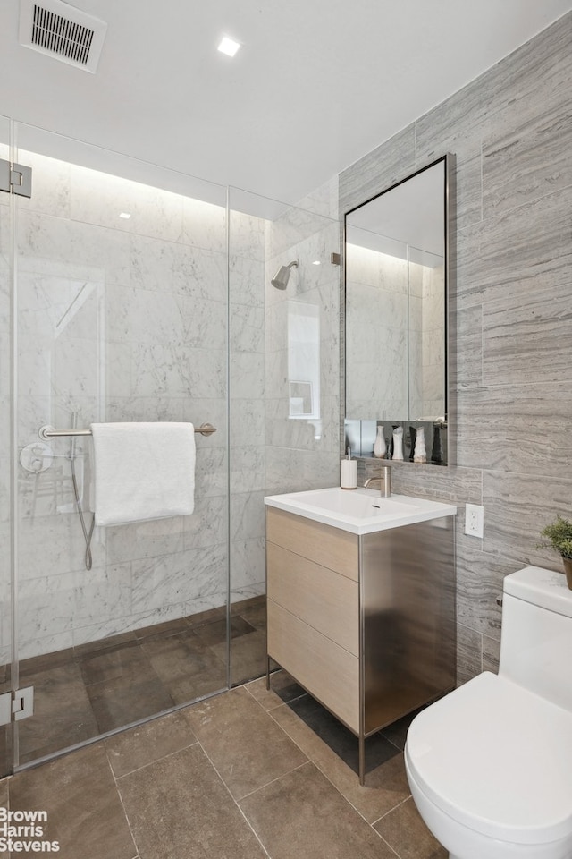 bathroom featuring visible vents, a shower stall, and tile walls