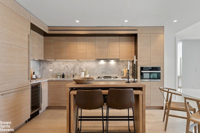 kitchen featuring a sink, light countertops, appliances with stainless steel finishes, light brown cabinetry, and modern cabinets