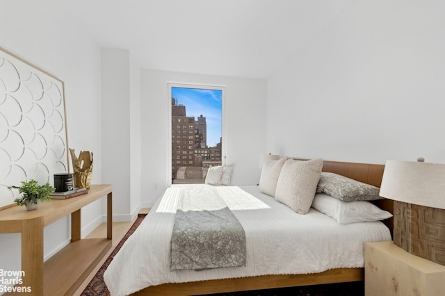 bedroom featuring a view of city, baseboards, and wood finished floors