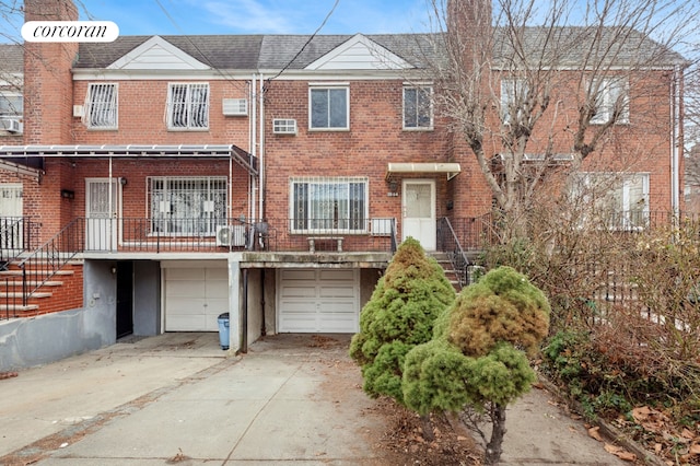 townhome / multi-family property with driveway, brick siding, and an attached garage