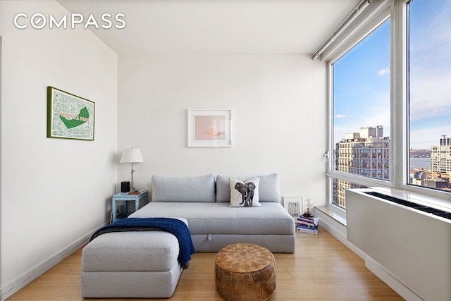 bedroom with a view of city, light wood finished floors, and baseboards