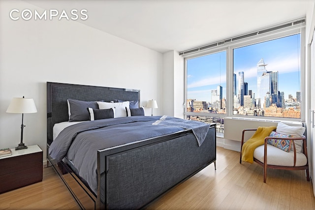 bedroom featuring a view of city and wood finished floors