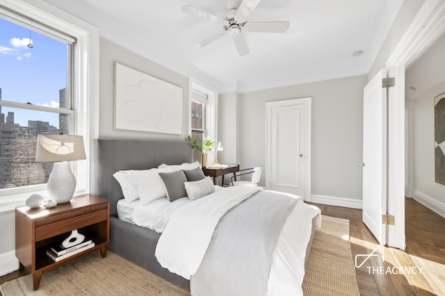 bedroom with ceiling fan, multiple windows, baseboards, and wood finished floors