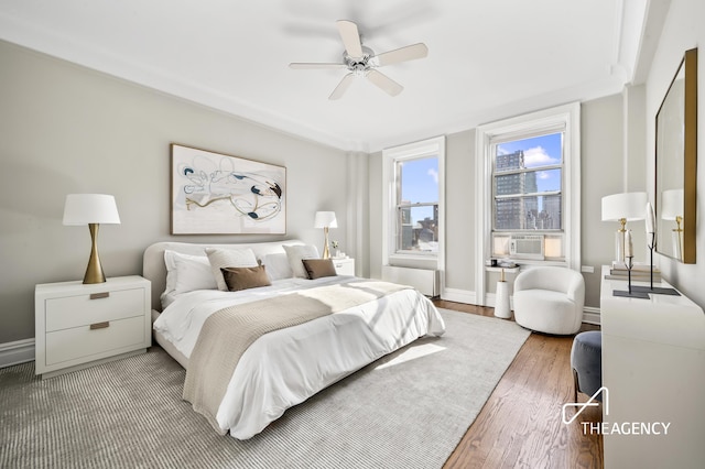 bedroom featuring light wood-style floors, baseboards, cooling unit, and a ceiling fan