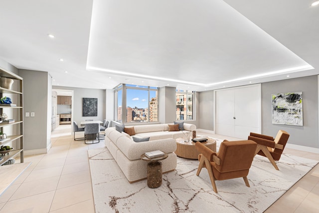 living room with baseboards, a tray ceiling, light tile patterned flooring, and recessed lighting