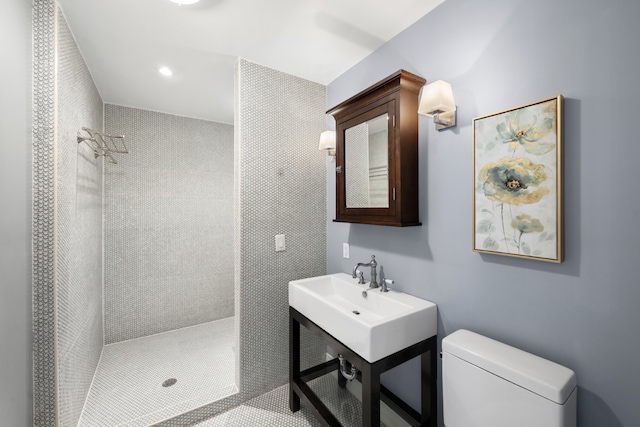 bathroom featuring recessed lighting, a sink, a tile shower, and toilet