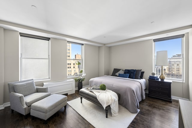 bedroom featuring dark wood-style floors, baseboards, and a city view