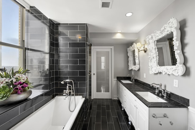 bathroom featuring double vanity, tiled bath, visible vents, and a sink