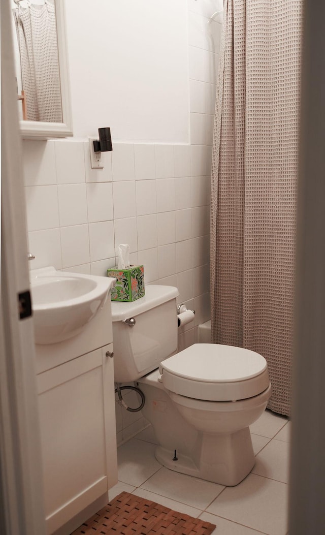 full bath with shower / tub combo with curtain, tile walls, toilet, vanity, and tile patterned flooring