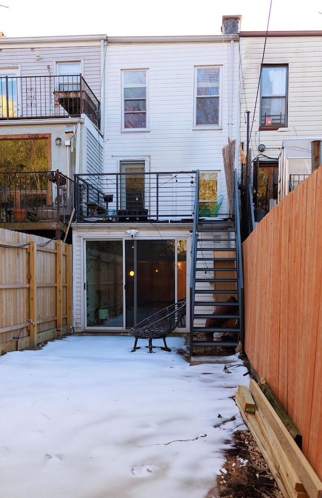 rear view of property featuring stairway and fence