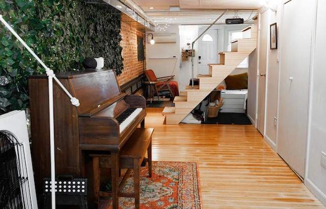 interior space featuring stairs, brick wall, and wood finished floors