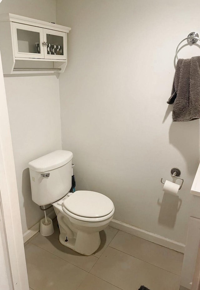 bathroom with toilet, baseboards, and tile patterned floors