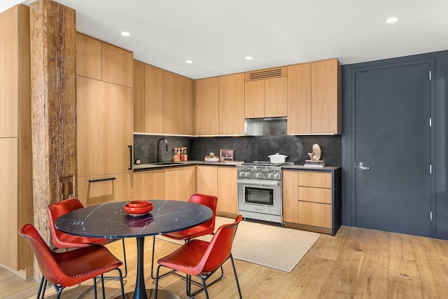 kitchen with light wood-style floors, visible vents, a sink, and high end stainless steel range