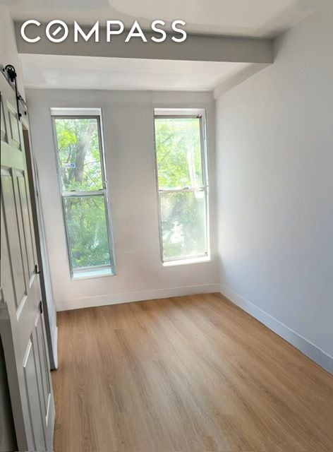 spare room with a barn door, light wood finished floors, baseboards, and healthy amount of natural light